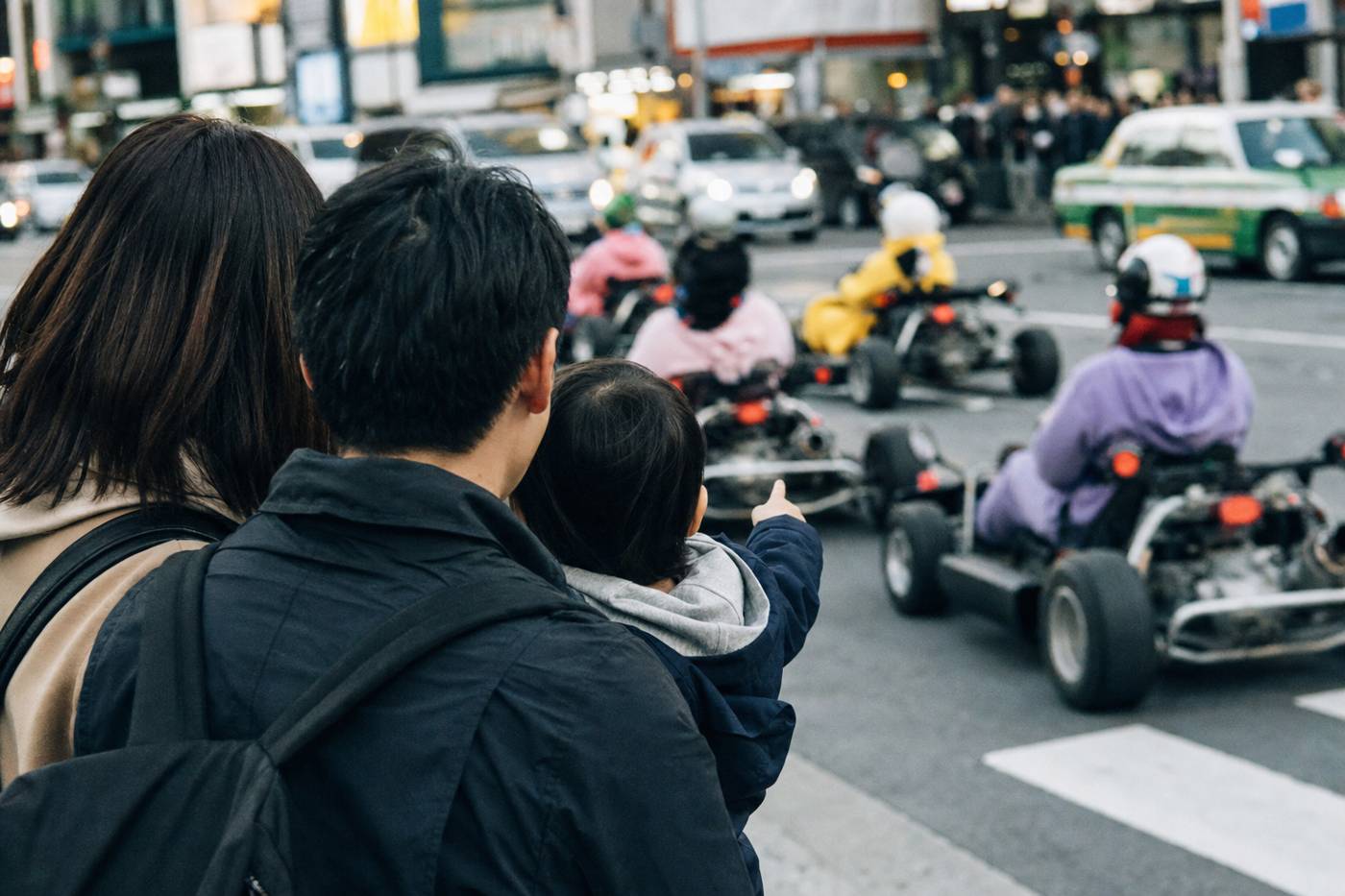 A family watching a Tokyo go-kart convoy pass in Shibuya