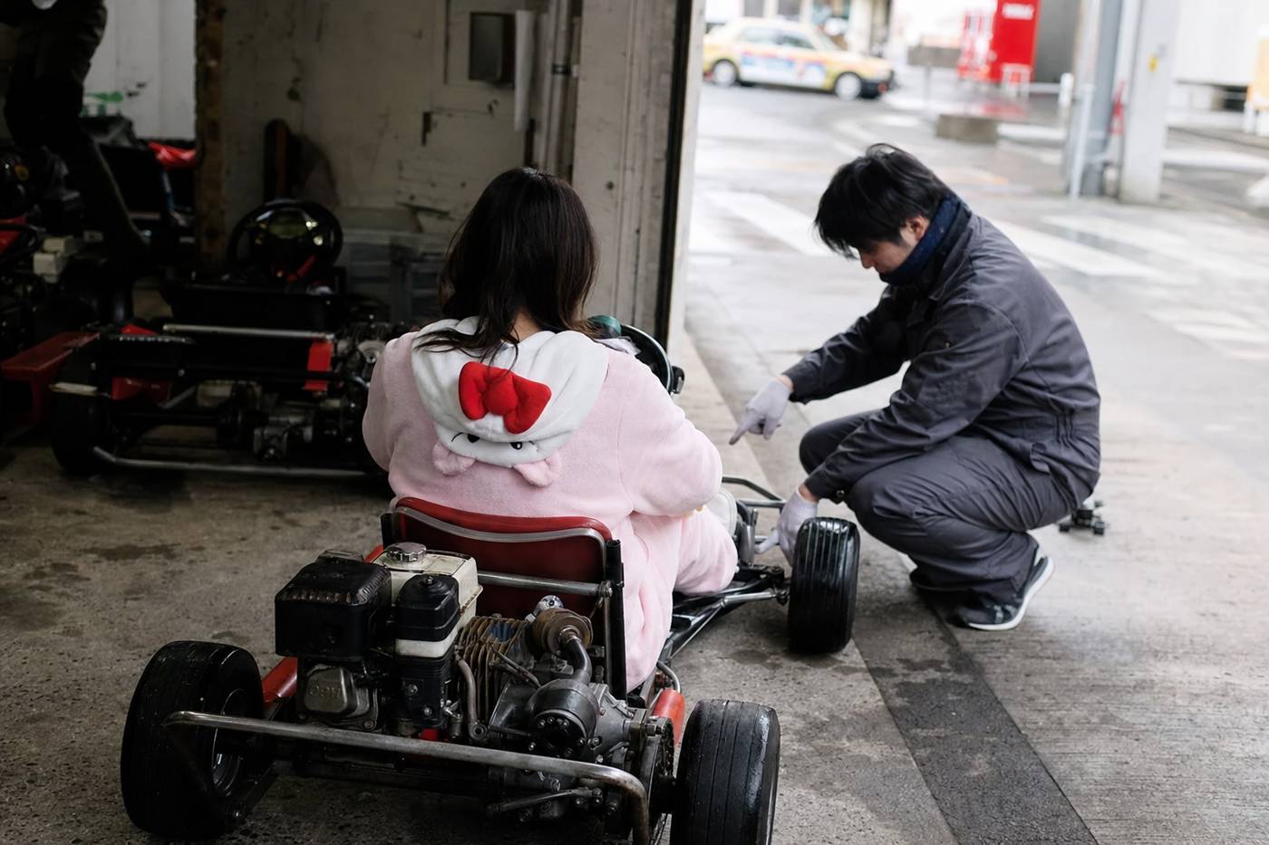 A first-time driver being shown the go-kart controls in a Tokyo garage