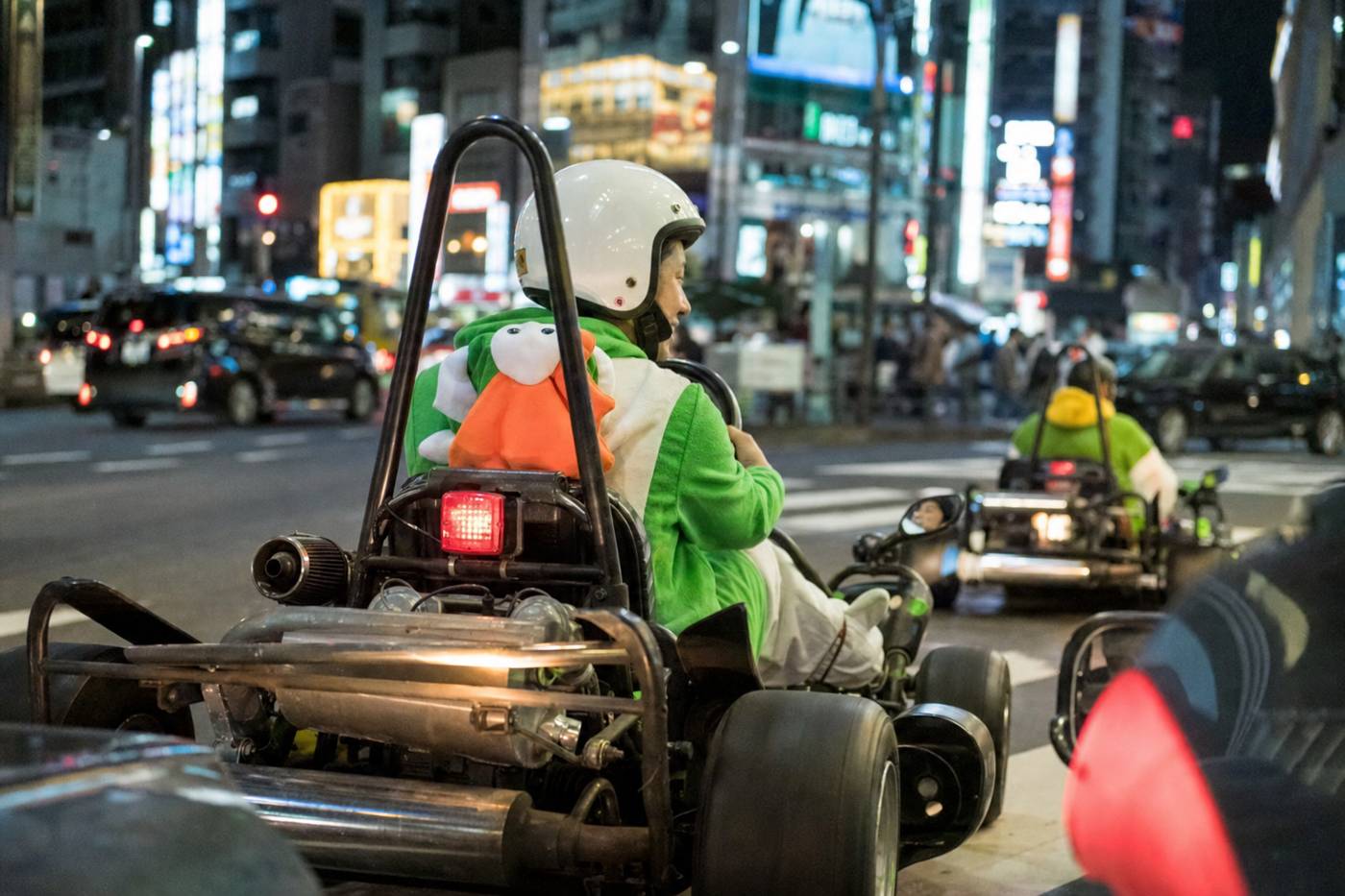 Helmeted driver enjoying a street go-kart ride through neon Shibuya