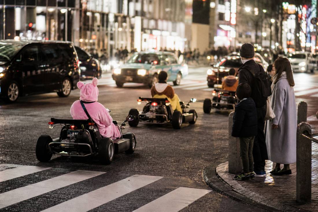 A go-kart group passing a family at Shibuya Crossing