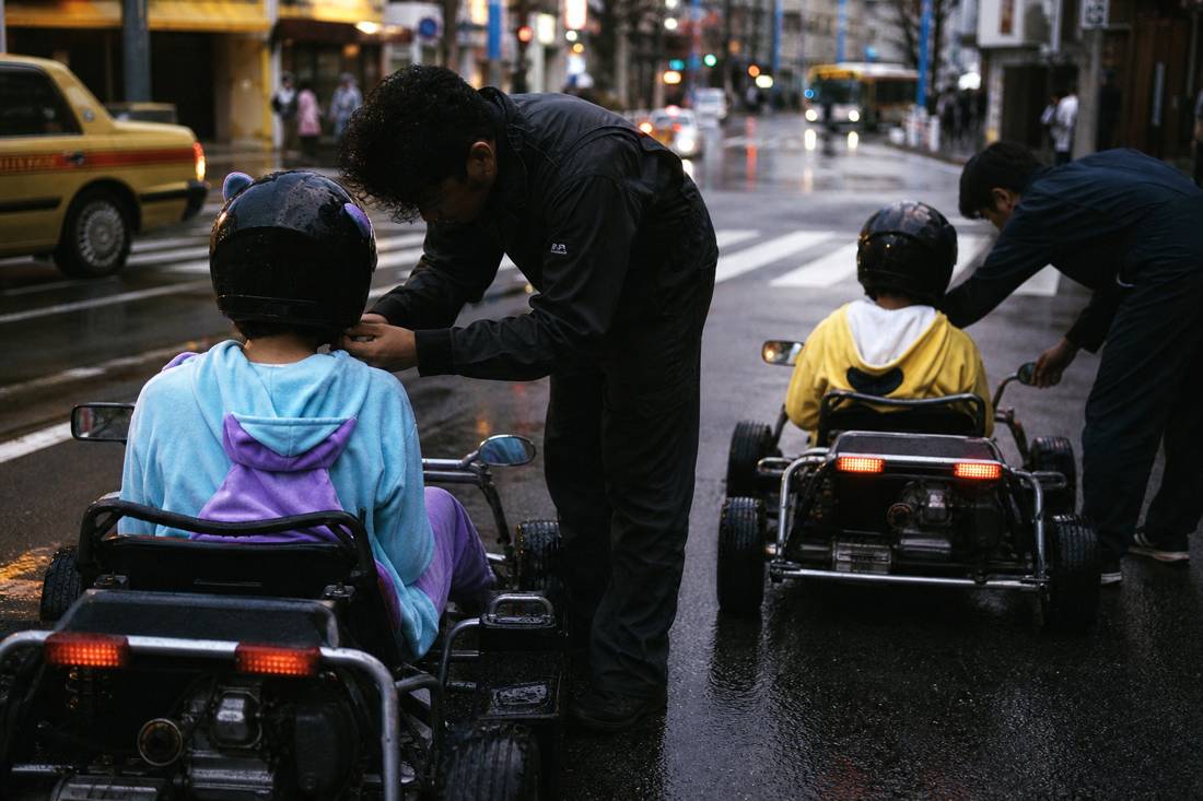 Staff fitting drivers into go-karts in a Tokyo garage