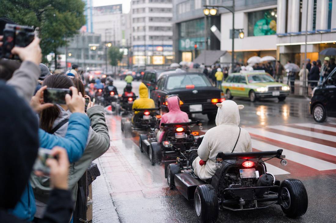 Pedestrians photographing a Tokyo go-kart convoy at Shibuya Crossing