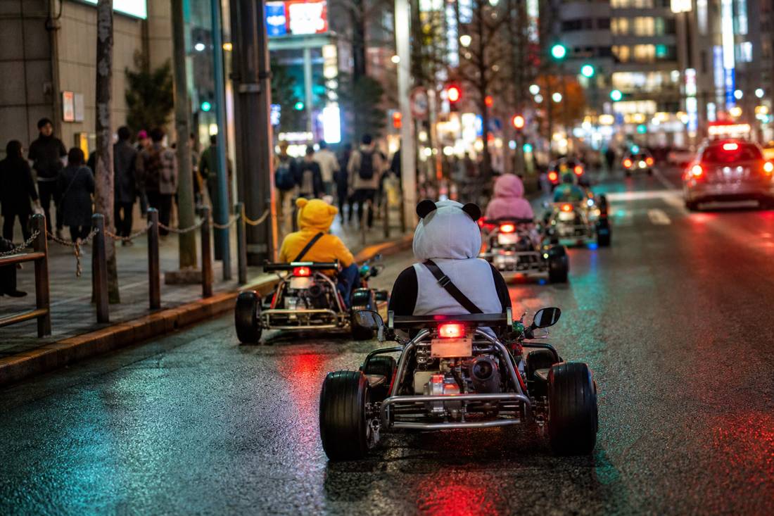 Street go-karts on the Shibuya Scramble at night with neon reflections