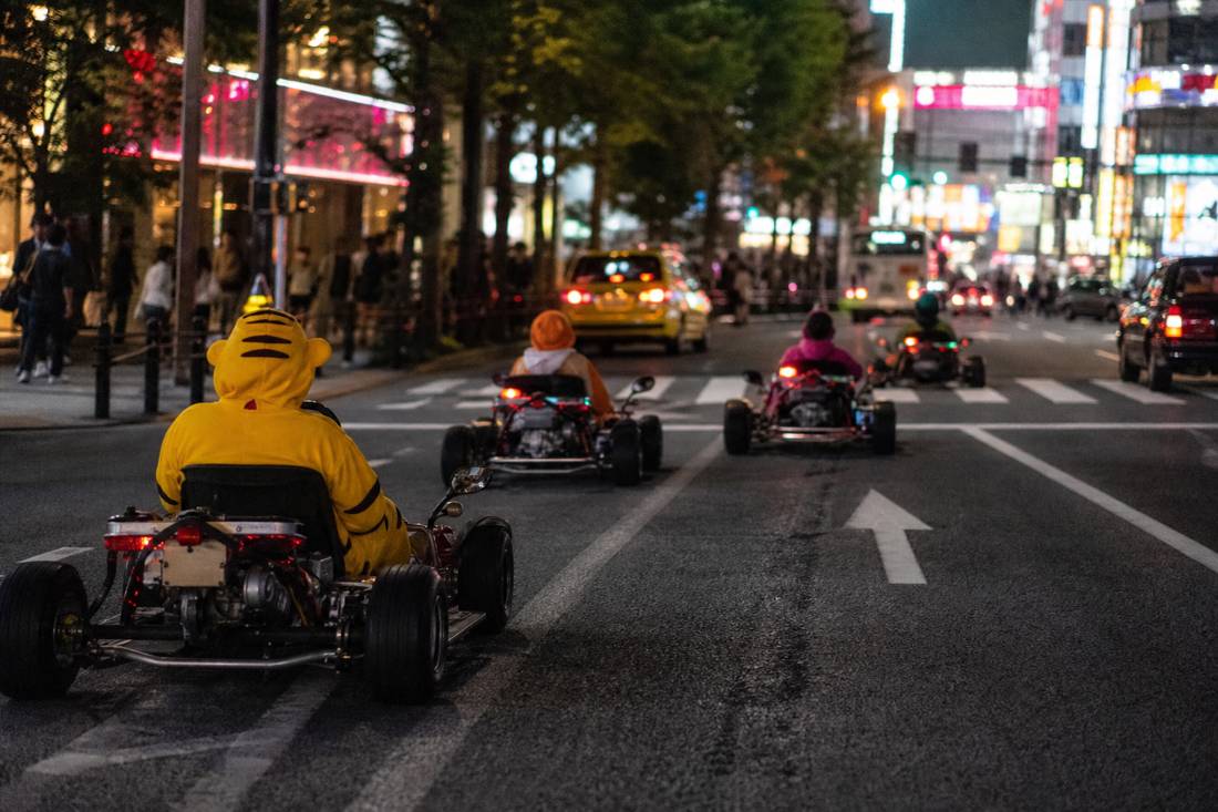 A guide leading a spaced go-kart convoy down a Tokyo avenue