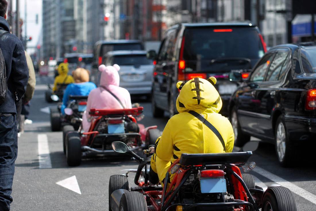 Go-karts at street level in dense Tokyo traffic beside taxis
