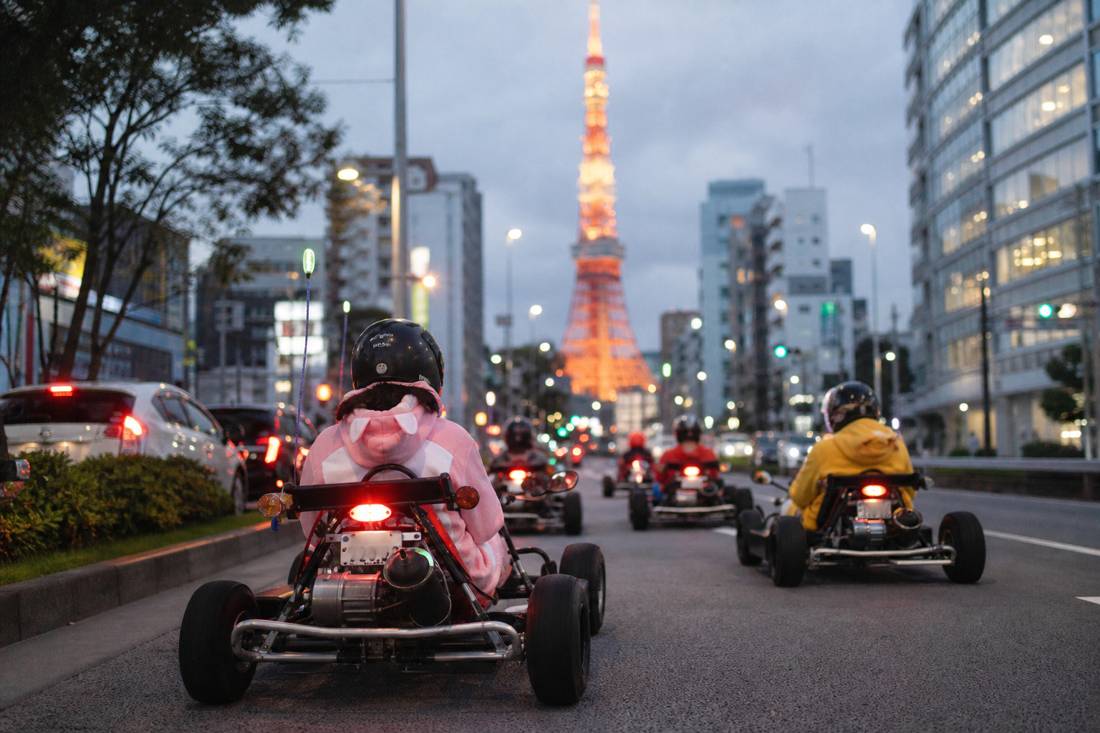 Go-karts driving toward the lit Tokyo Tower in the evening