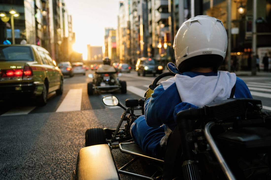 Helmeted driver steering a street go-kart through Shinjuku