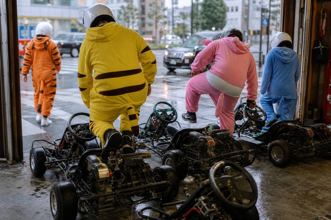 A group in costumes boarding go-karts at a Tokyo garage