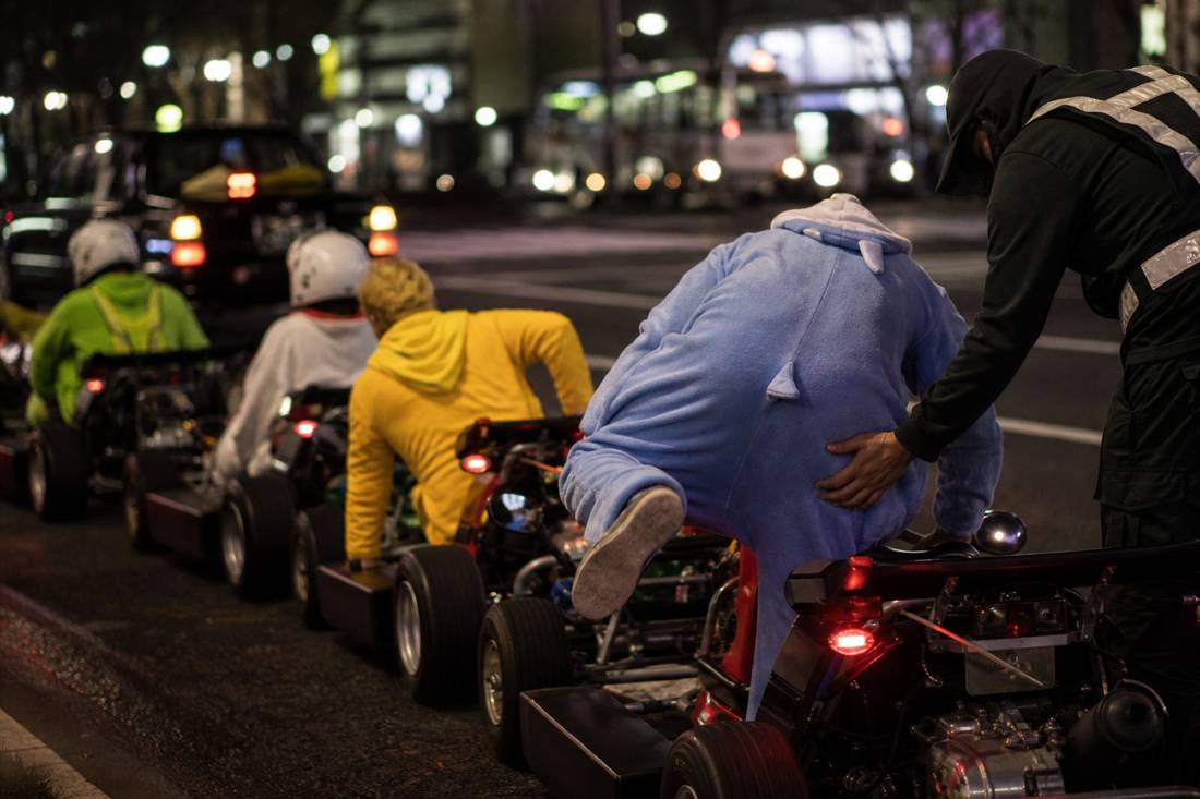 Drivers stepping into low go-kart seats in a Tokyo garage