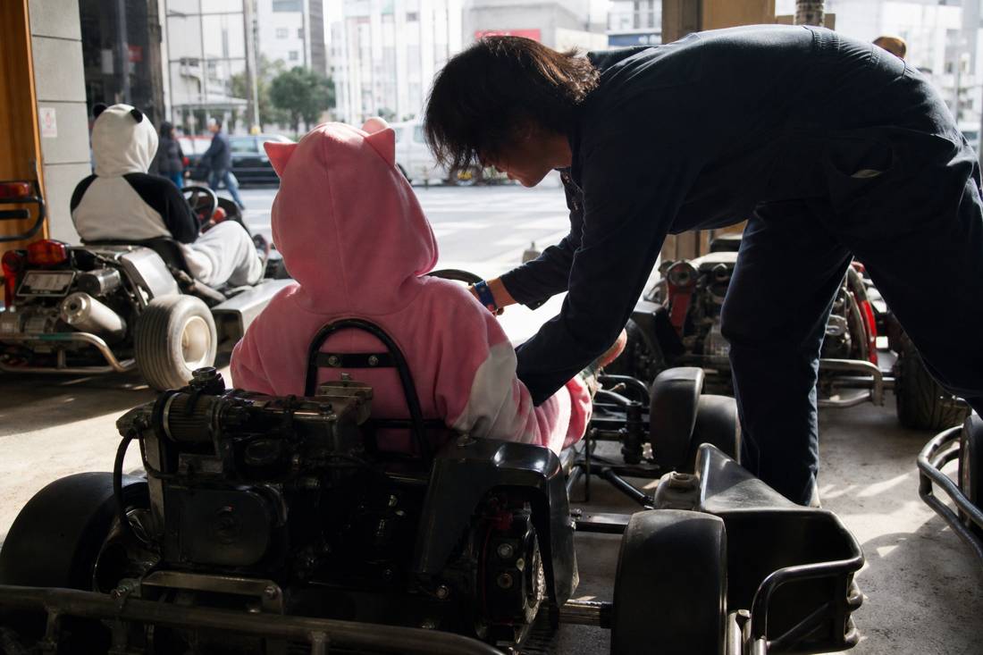 Staff helping an older driver into a go-kart seat