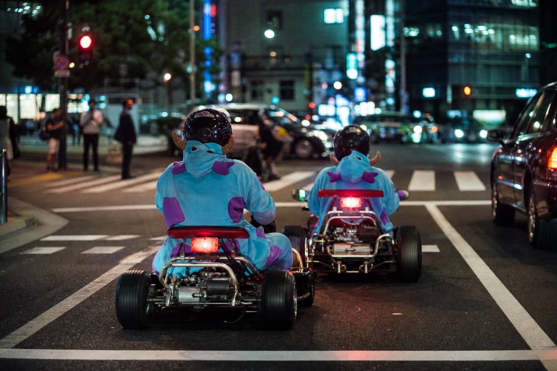 An older couple on go-karts at a Tokyo red light