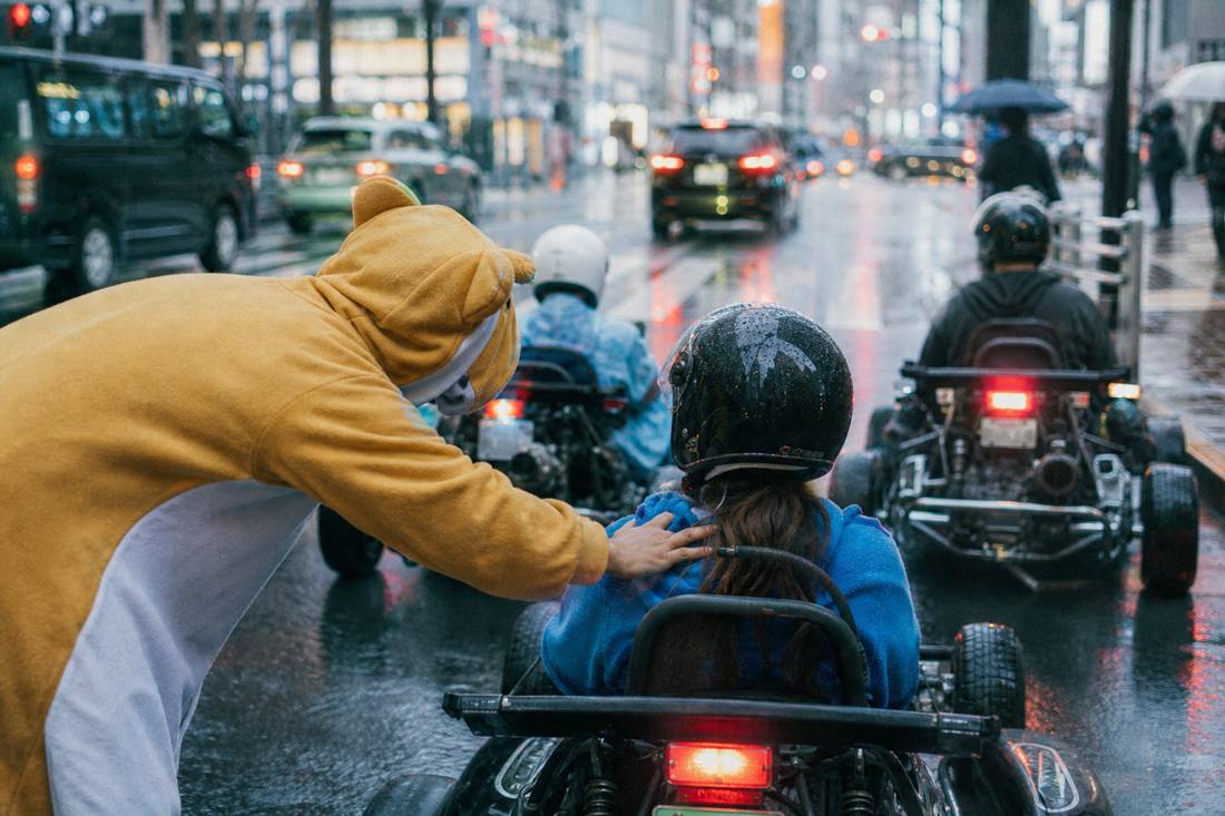 A guide checking on a go-kart driver at a stop in Tokyo