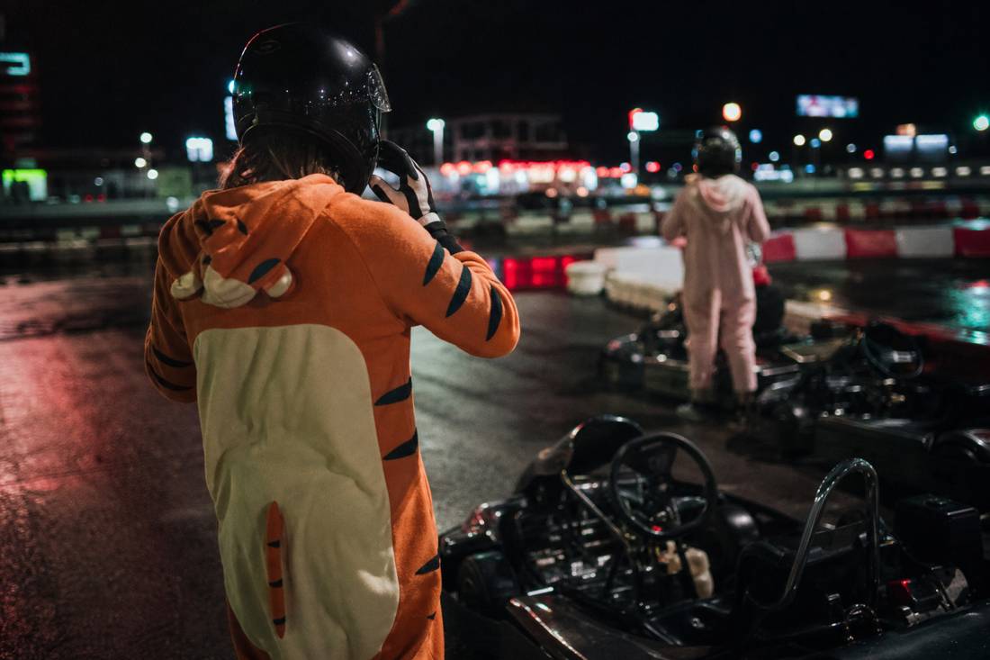 A driver pulling on gloves and helmet beside a go-kart